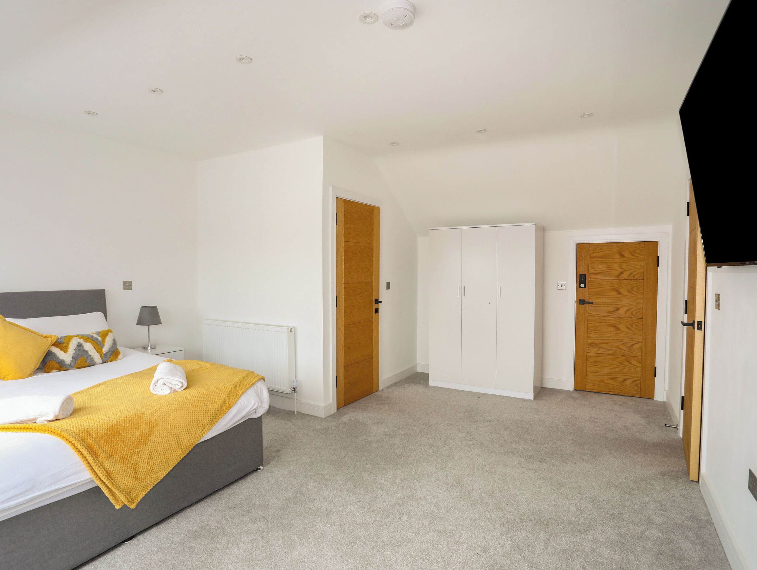 Un dormitorio con cama, armario, radiador y puerta.
