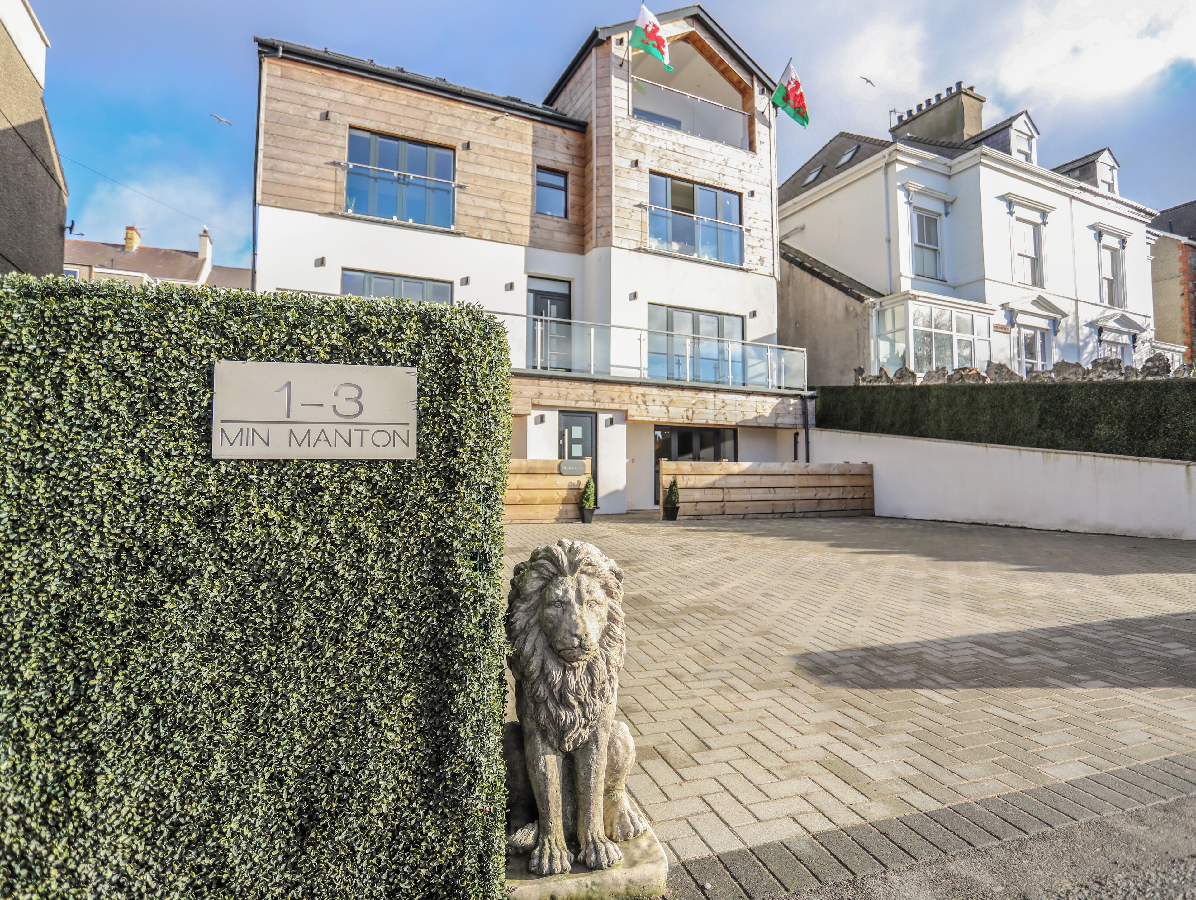 A building with a sign reading "1-3 MIN MANTON" and a stone lion statue in front.
