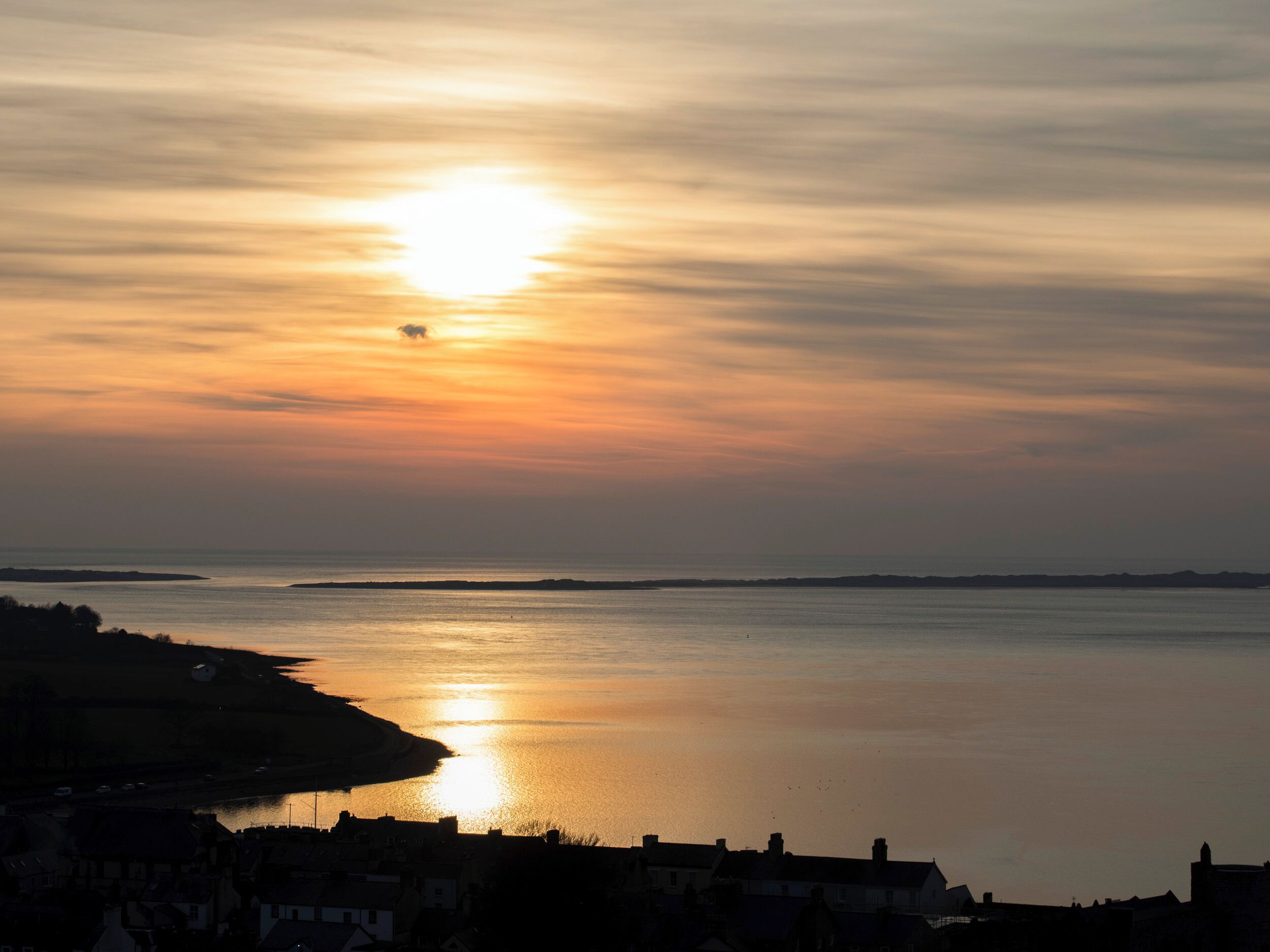 A coastal sunset with a calm sea reflecting the sky.