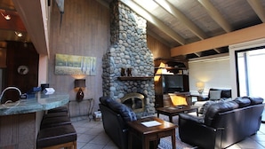 A cozy living area with a stone fireplace, comfortable seating, and a bar counter. - Llc1236 - Lakeside Landing 4 Bedroom Condo (South Lake Tahoe)