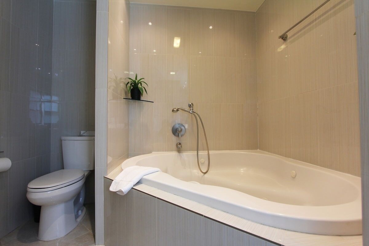 Un baño moderno con una bañera independiente, un inodoro y un estante con una planta.
