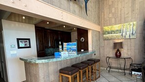A bar area with a wooden counter, bar stools, a large fish decoration, a framed picture, and a lamp. - Llc1236 - Lakeside Landing 4 Bedroom Condo (South Lake Tahoe)
