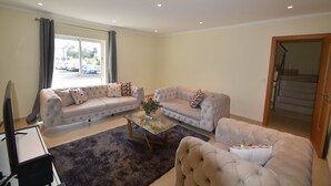 A living room with two sofas, a coffee table, and a TV. - Villa Machado is located in Alcantarilha with a private swimming pool. (Alcantarilha)
