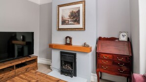 Una sala de estar con chimenea, televisor y un aparador de madera.