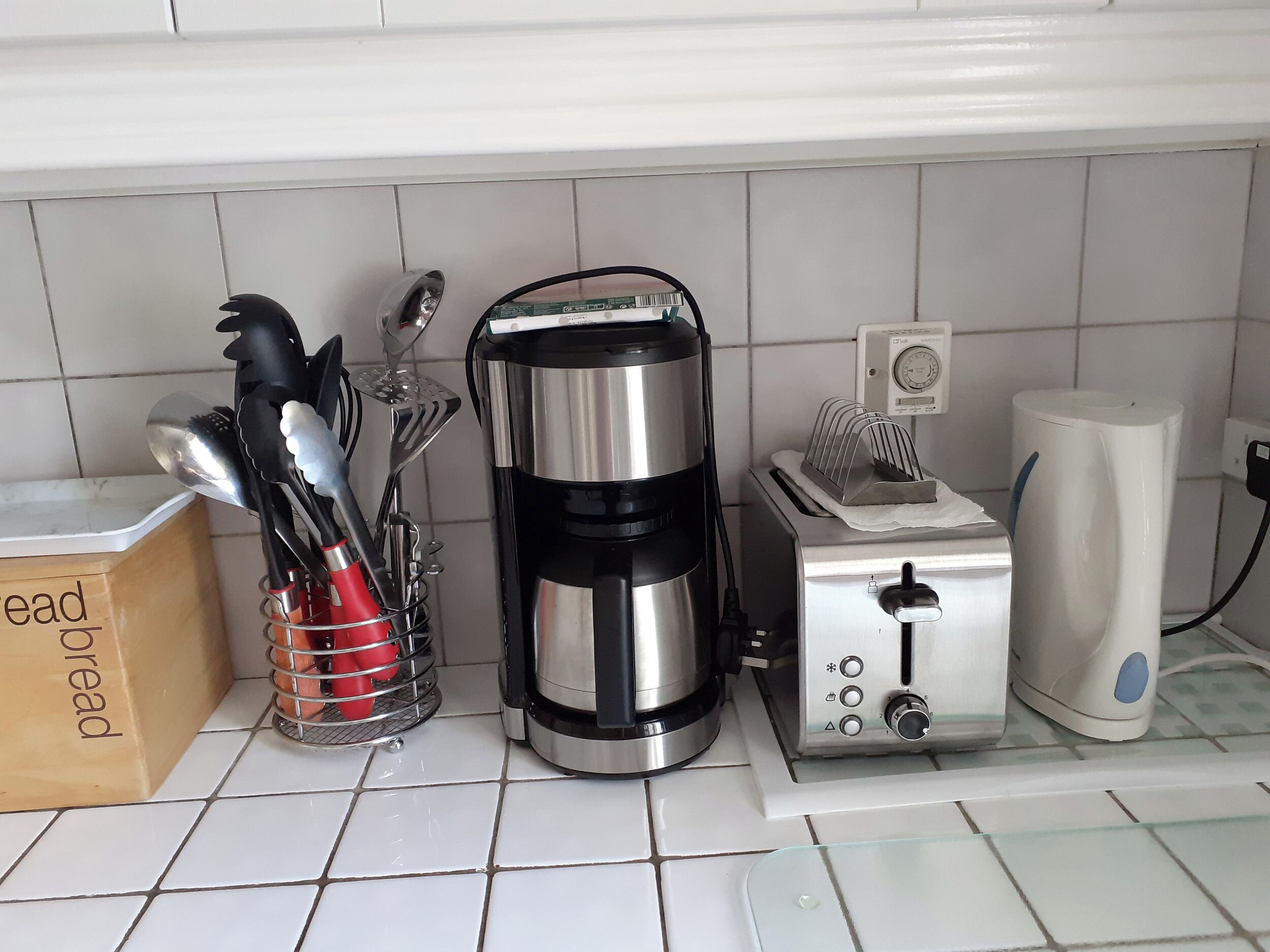 A kitchen with a coffee maker, toaster, and utensils on the counter.