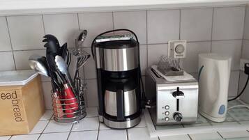 A kitchen with a coffee maker, toaster, and utensils on the counter.