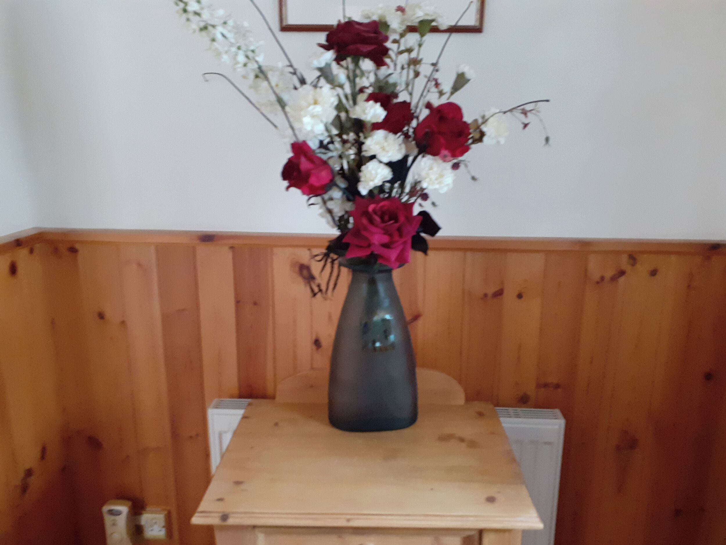 Ett träbord med en vas med blommor.