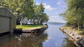 A calm water body with a wooden dock, surrounded by trees and a grassy area.