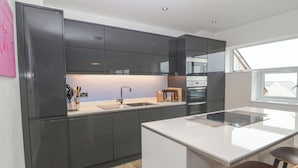 Eine moderne Küche mit dunklen Schränken, einer weißen Arbeitsplatte und einem eingebauten Backofen.