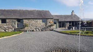 A stone building with a gravel driveway and a fountain.