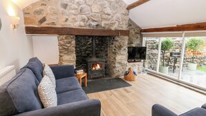 A cozy living room with a stone fireplace, a comfortable sofa, and a television.