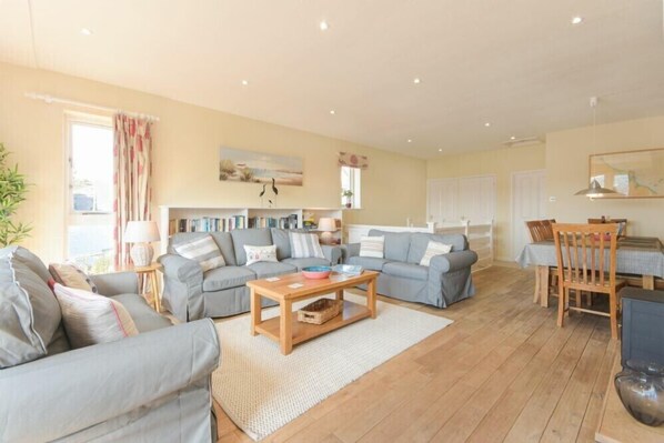 A spacious living room with a sofa set, a wooden coffee table, and a dining area with a table and chairs.