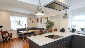 A modern kitchen with a central island, dark cabinetry, and wooden flooring.