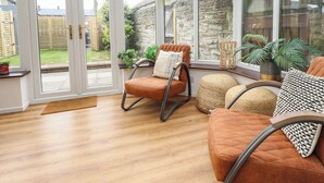 A conservatory with a wooden floor, a rocking chair, and a sofa.