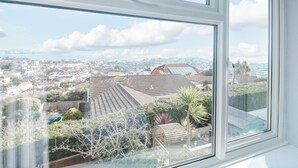 A view from a window overlooking a residential area with houses and a distant cityscape.