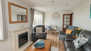 A living room with a fireplace, a dining table with chairs, a sofa, and a coffee table.