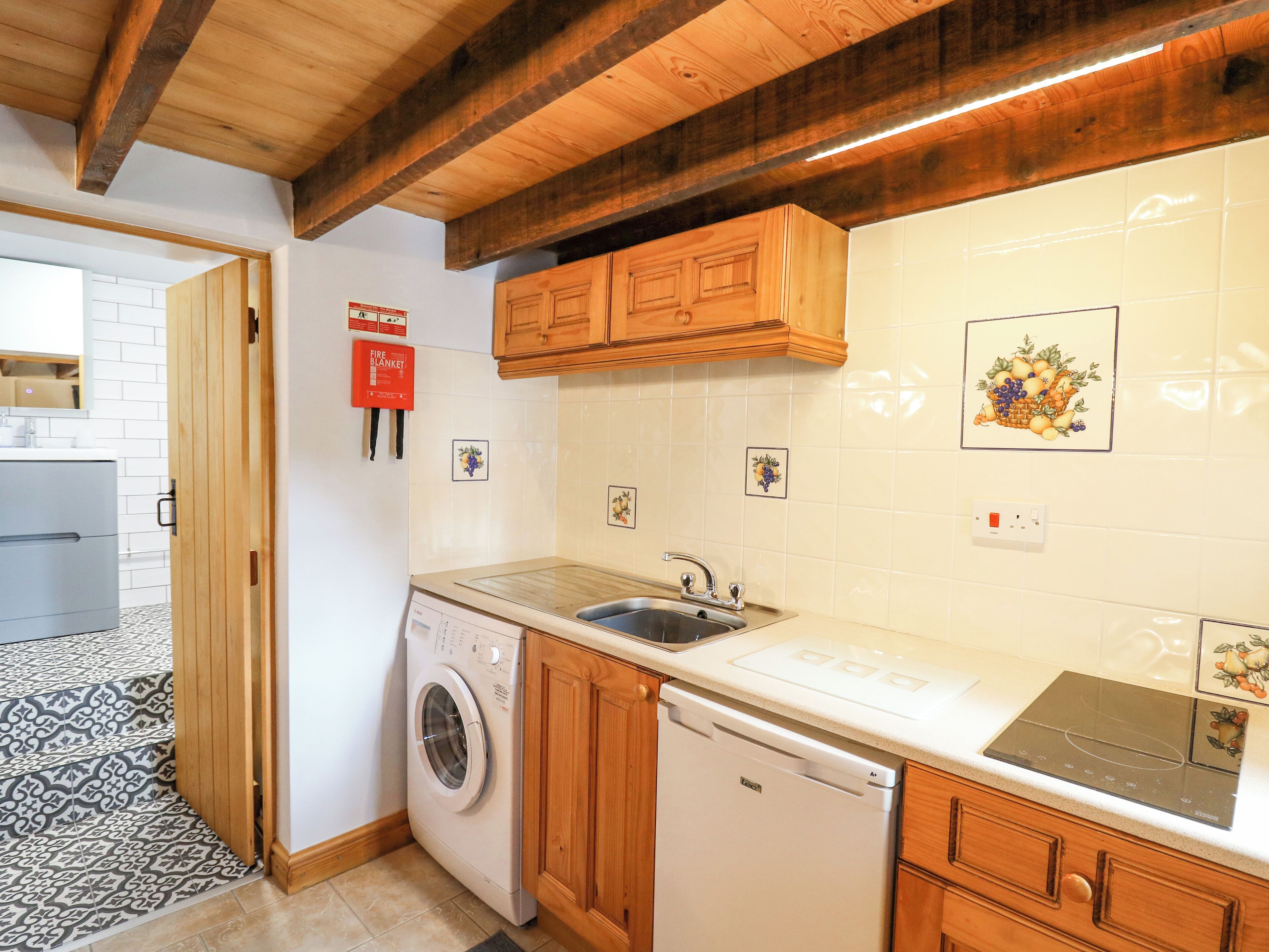 A compact kitchen with wooden cabinets, a washing machine, a dishwasher, and a sink.