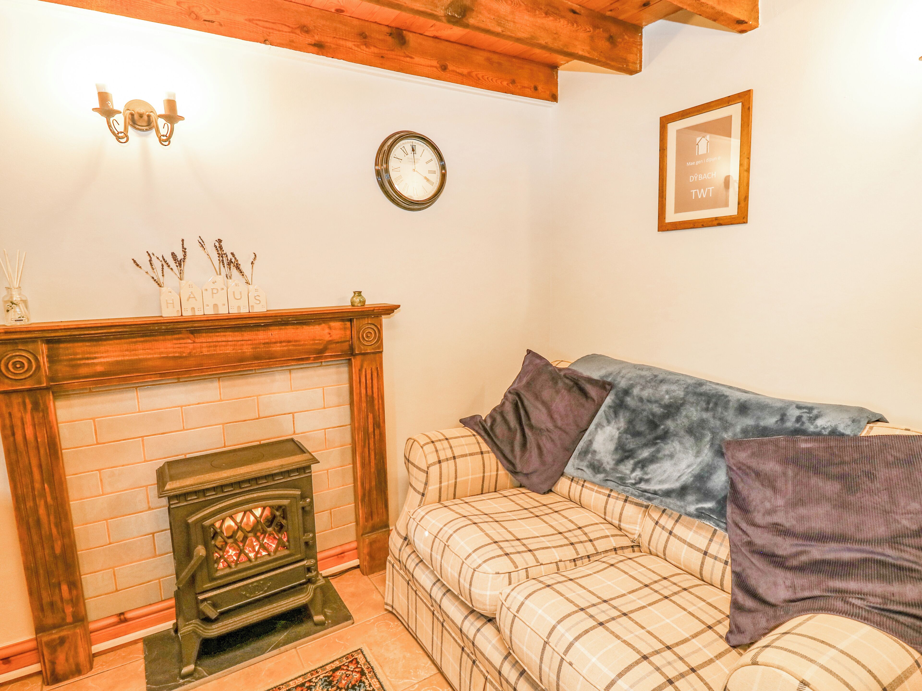 A cozy living room with a fireplace, a sofa, and a clock on the wall.