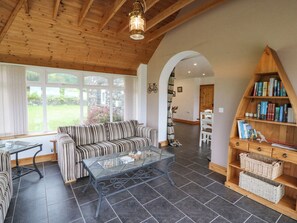 A cozy living room with a striped sofa, a glass coffee table, and a wooden bookshelf. - Coorlacka (Goleen)