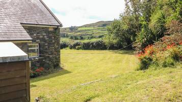 A stone house with a sloped roof and a grassy yard.