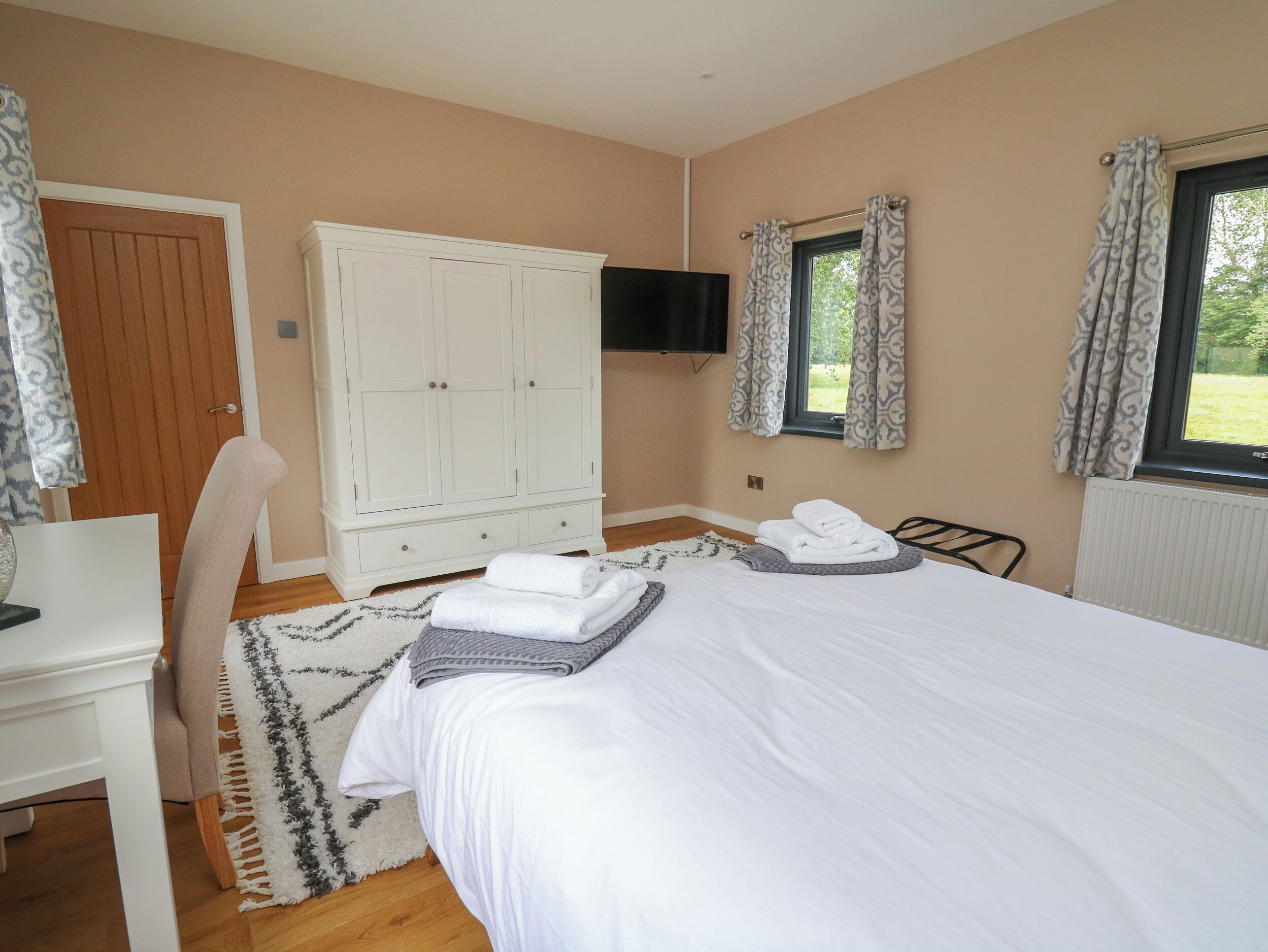 Un dormitorio con cama, armario, escritorio y televisor.