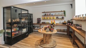 Ein Ladeninneres mit Holzboden, einem runden Tisch in der Mitte, Regalen mit Gläsern und Kartons sowie einer Kühlvitrine.