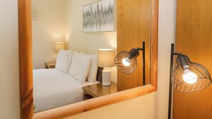 Ein Hotelzimmer mit einem Bett, Nachttischlampen, einem Holzschrank und einem gerahmten Kunstwerk an der Wand.