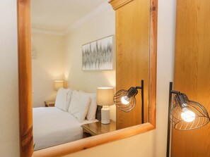 Une chambre d’hôtel avec un lit, des lampes de chevet, une armoire en bois et une œuvre d’art encadrée au mur.