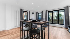 Una cocina moderna con una mesa de comedor para cuatro, ventanas amplias y vista al vecindario.