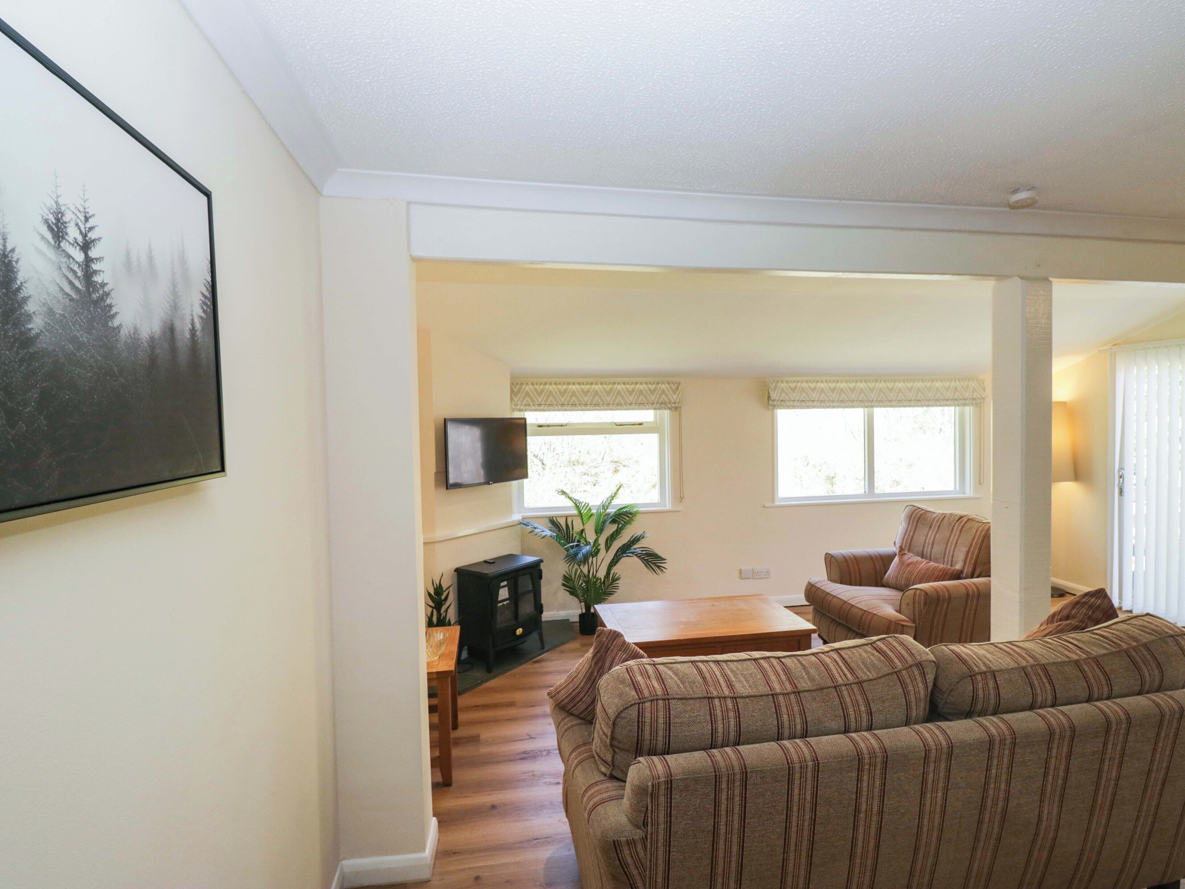 A living room with a sofa, a television, a fireplace, and a dining area.
