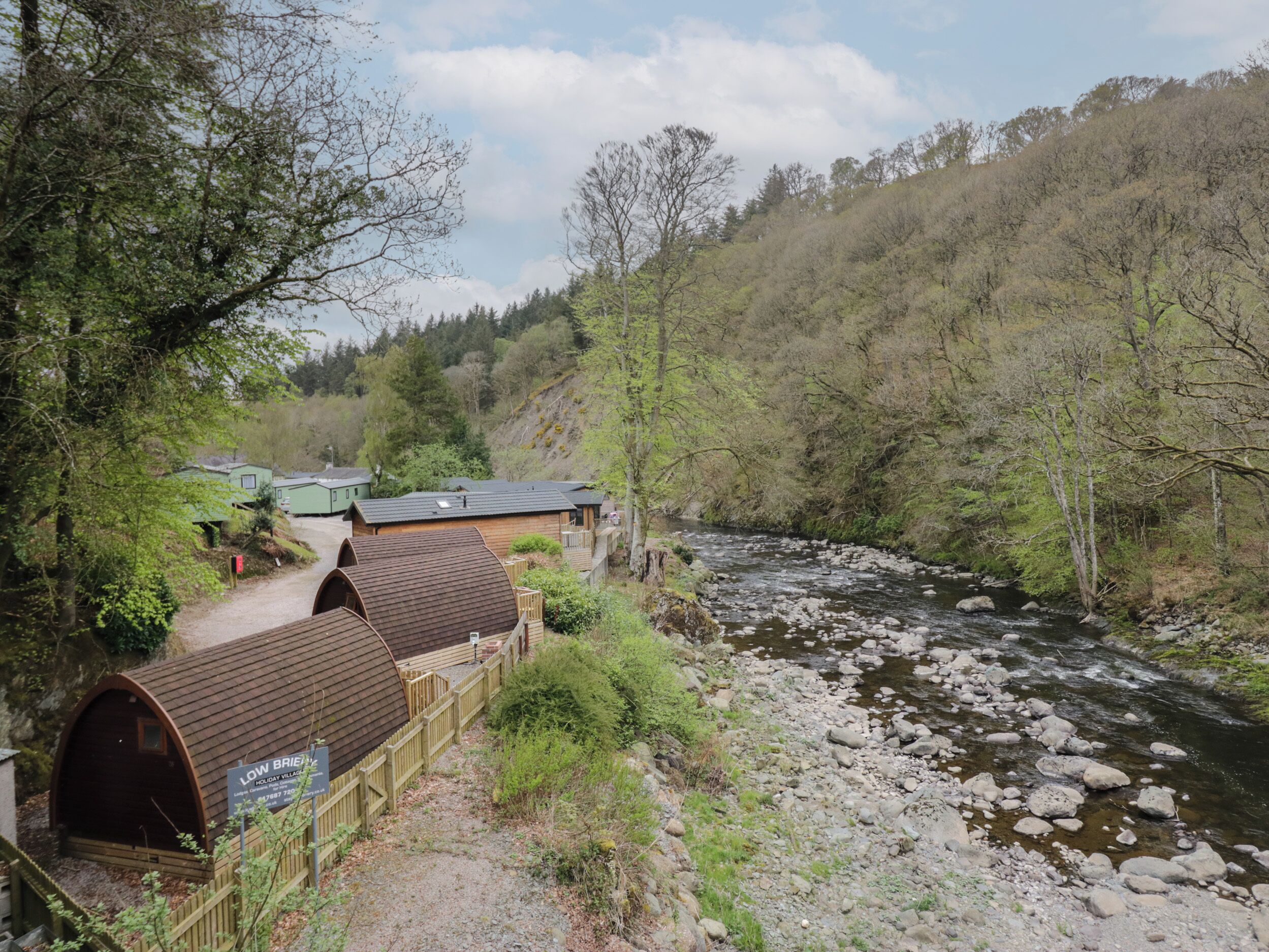 A riverside accommodation with wooden cabins and a wooden walkway.