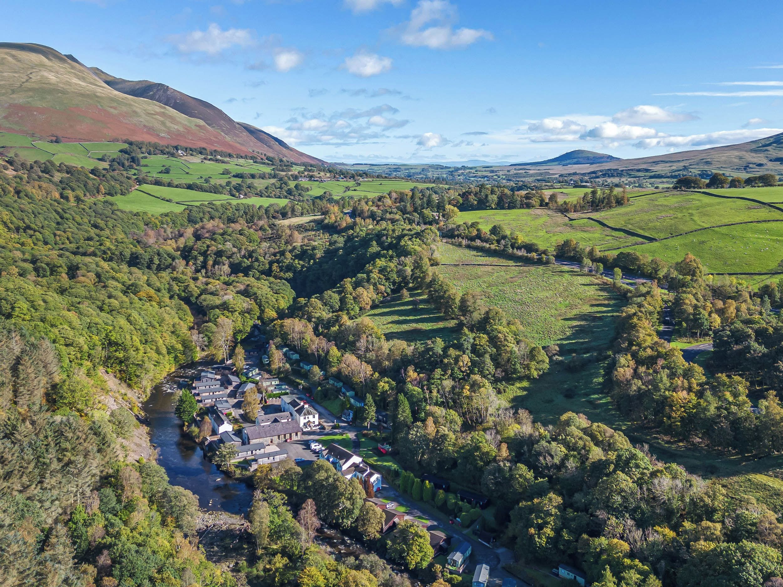 A rural landscape with a valley, a river, and scattered houses.