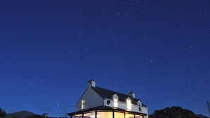 A house with a large glass front, a stone base, and a dark roof. - Casey House (Castletownbere)