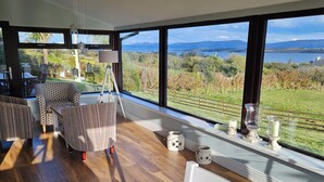 A modern living room with a large window overlooking a scenic landscape. - Casey House (Castletownbere)