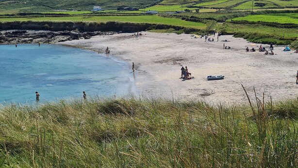A coastal beach with people, a small boat, and a hill in the background. - Casey House (Castletownbere)