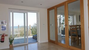A spacious room with a sliding glass door leading to a balcony, a fire extinguisher, and a small potted plant.