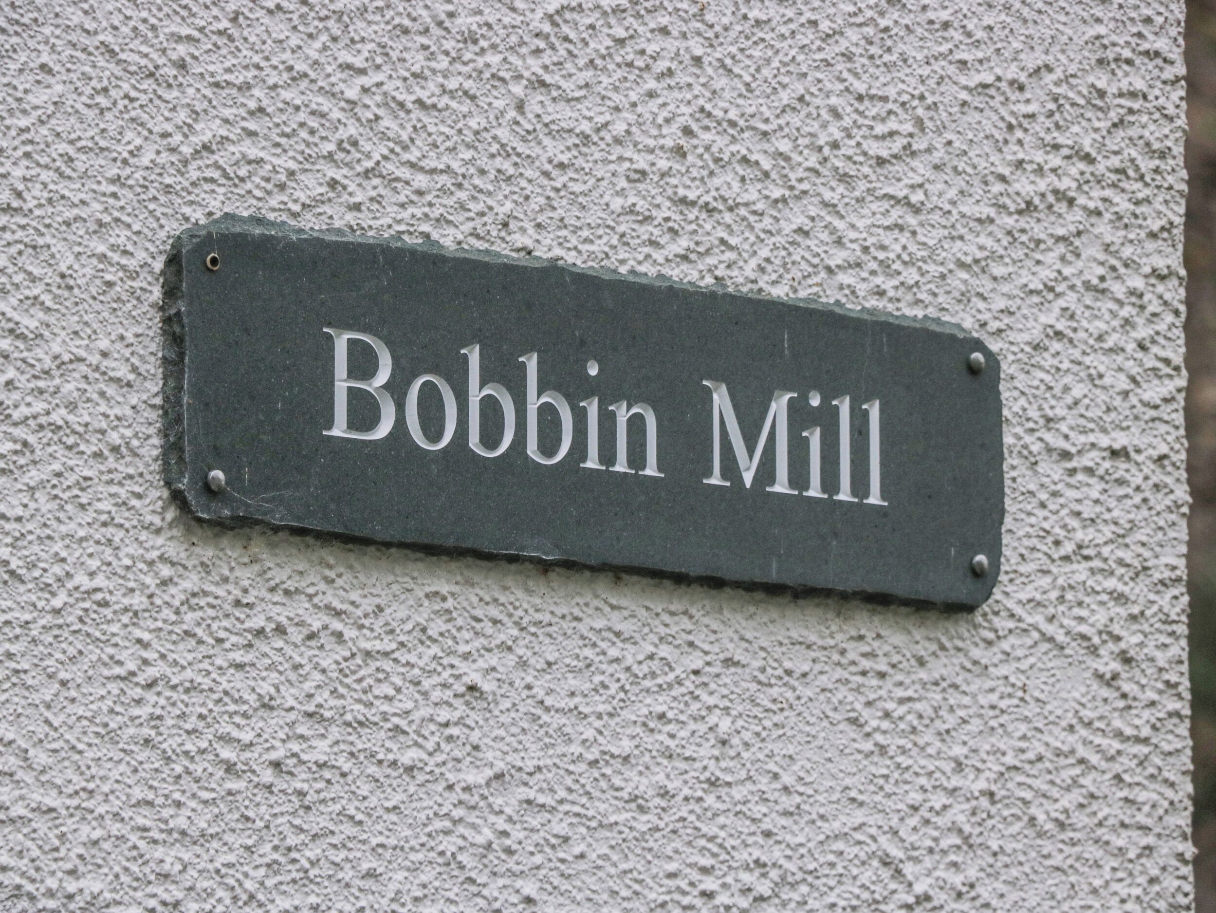 Une enseigne portant l'inscription « Bobbin Mill » est fixée à un mur à texture.