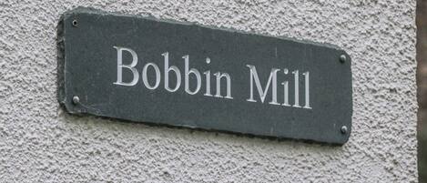 Une enseigne portant l'inscription « Bobbin Mill » est fixée à un mur à texture.