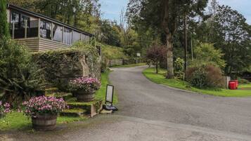 A rural road leading to a building with a stone wall and wooden structure.