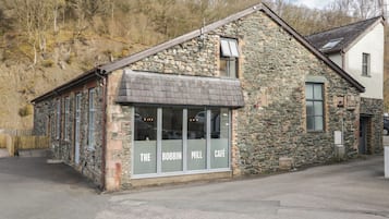 A stone building with a café sign, a window, and a door.