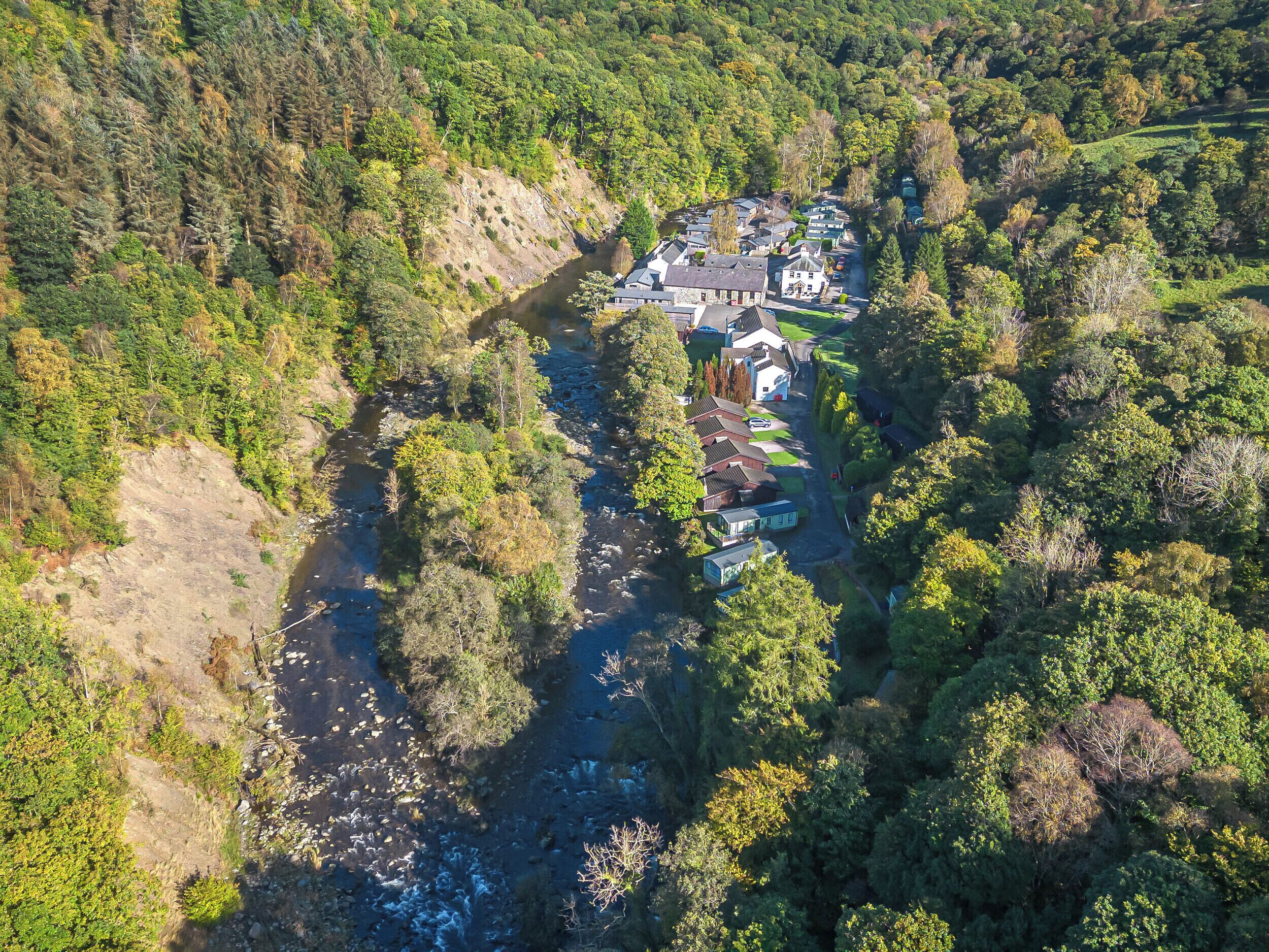 Vista aerea di una zona residenziale con case, un fiume e una fitta foresta.