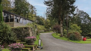 A rural road leading to a building with a stone wall and wooden structure.