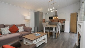 A modern living room with a sofa, coffee table, and dining area. - The Bothy (Keswick)