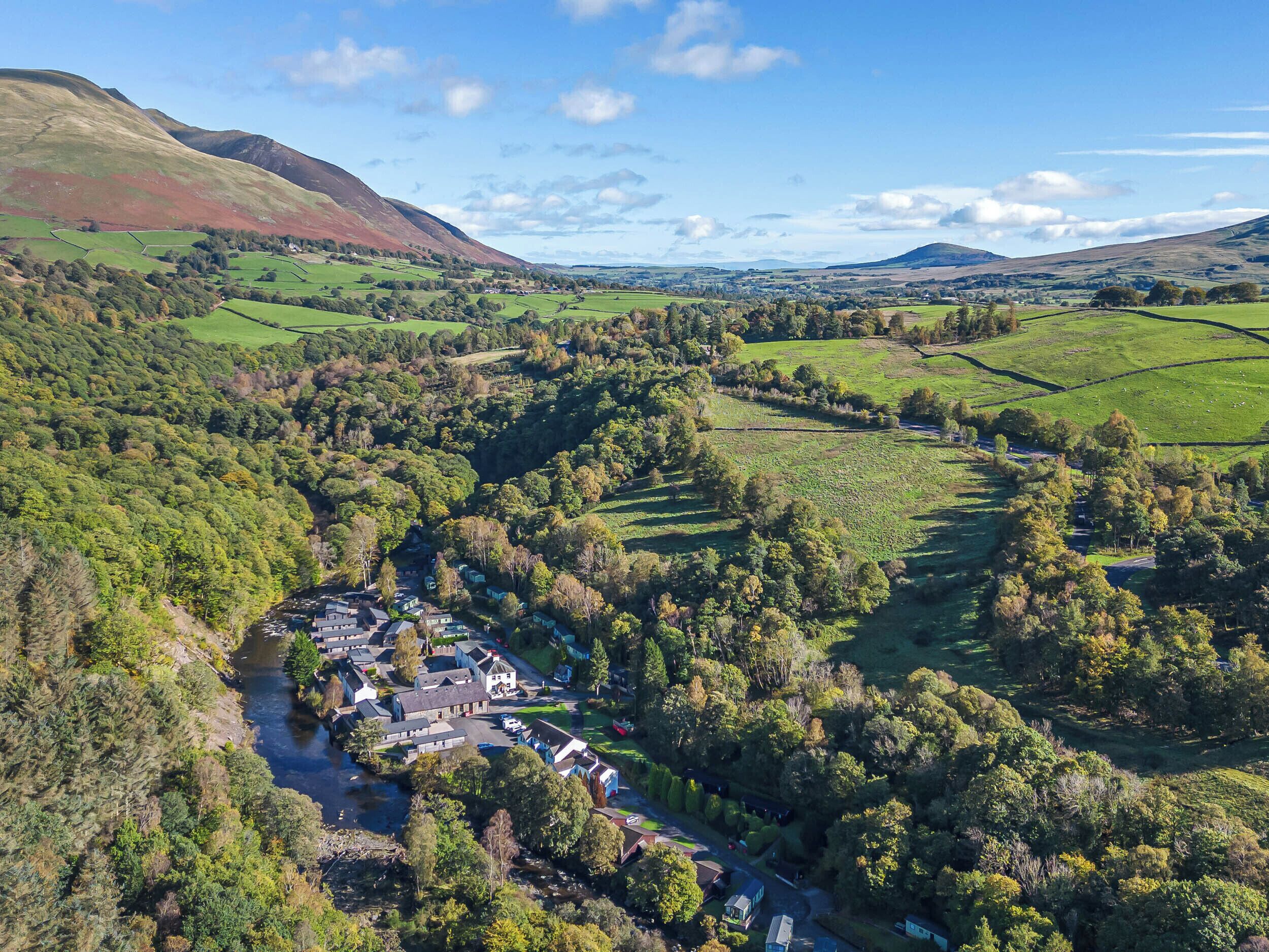 Un paysage rural avec une vallée, une rivière et des maisons éparpillées.