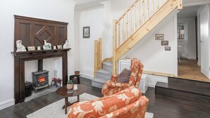 Un salon avec une cheminée, un canapé, un escalier et un couloir menant à une autre pièce.