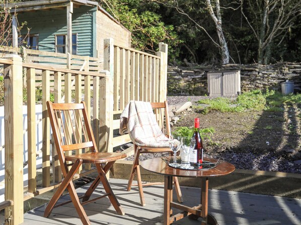 A wooden deck with two chairs and a table, a bottle of wine, and a glass on the table. - 4 Ty Person (Bangor)