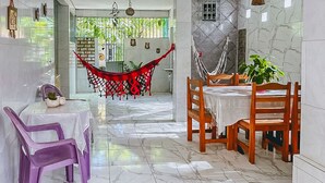 Zona pranzo con tavolo apparecchiato per due, un'amaca e vista sull'esterno.