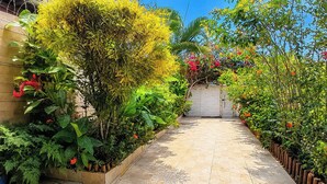 Un vialetto circondato da vegetazione lussureggiante e fiori che conduce a un cancello.
