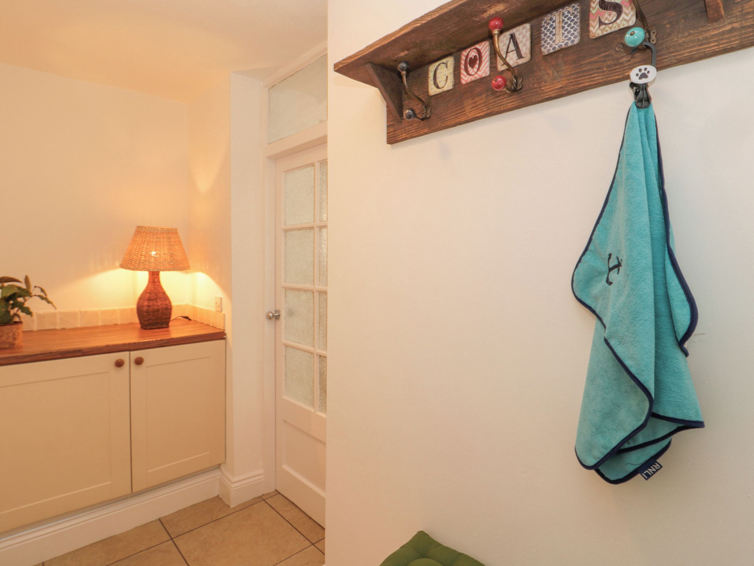 A kitchen with a wooden countertop, a lamp, and a towel hanging on a rack with letters and a paw print.