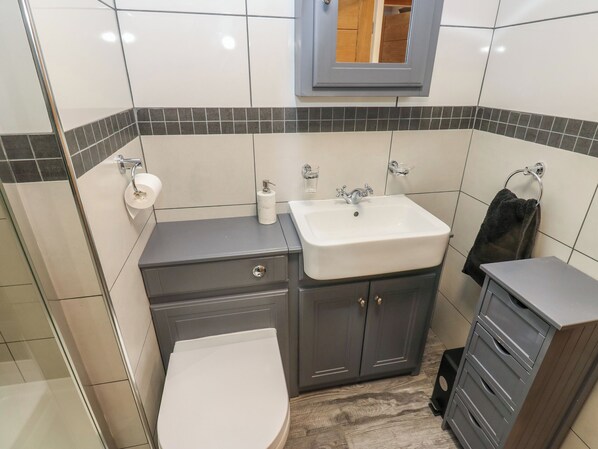 A bathroom with a white sink, a toilet, and a vanity with drawers. - Pickwood Grange (Sowerby Bridge)